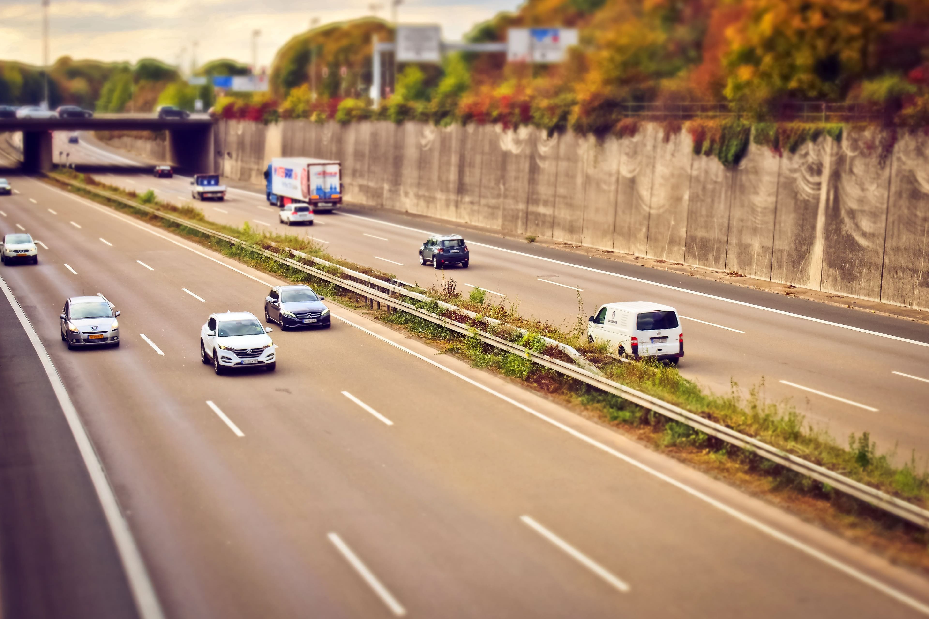 Cars and lorries moving along a sunlit highway, representing a Malaysian motorist's daily drive on a currently licensed vehicle.