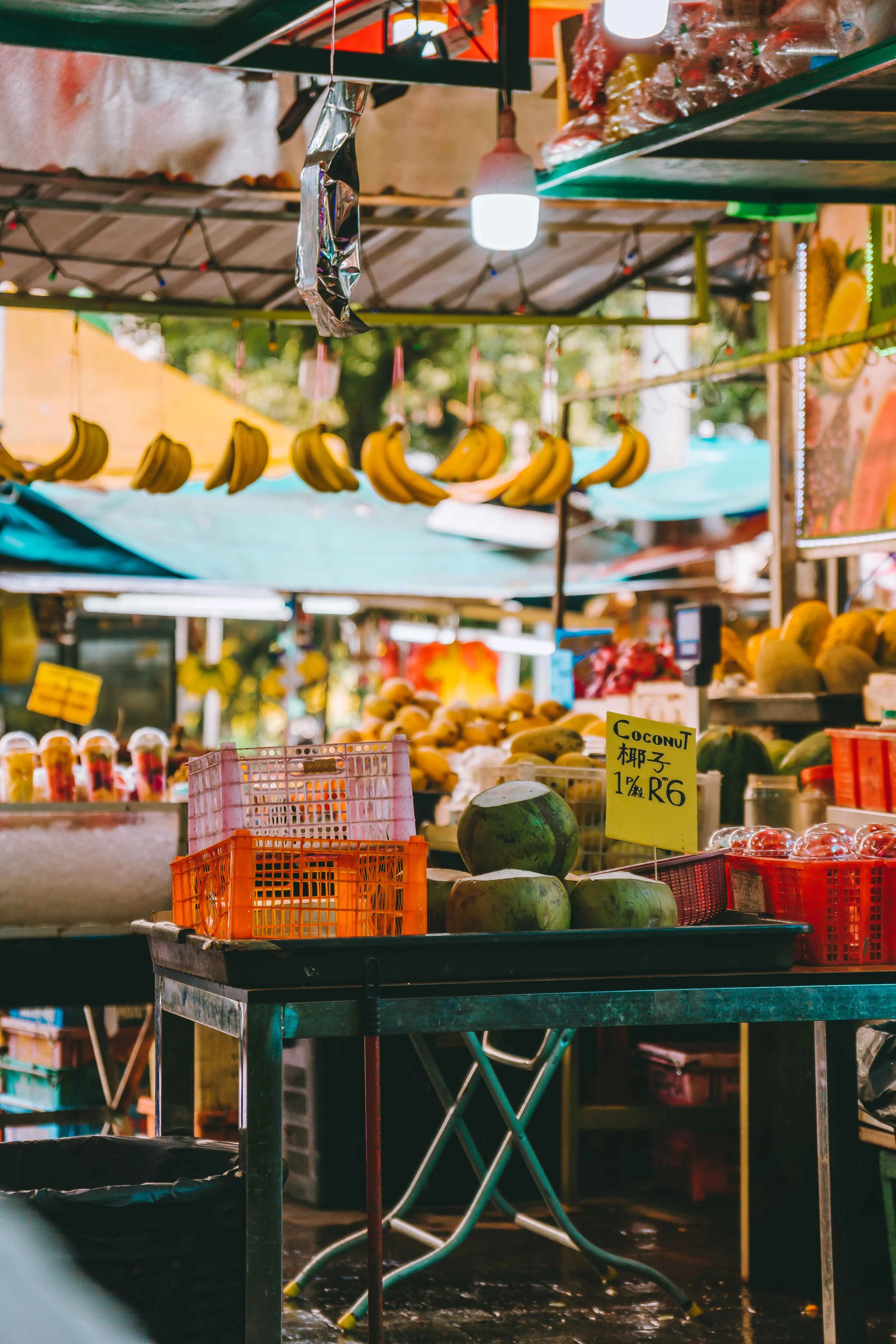 A busy outdoor market stall stacked with tropical fruit and local produce.