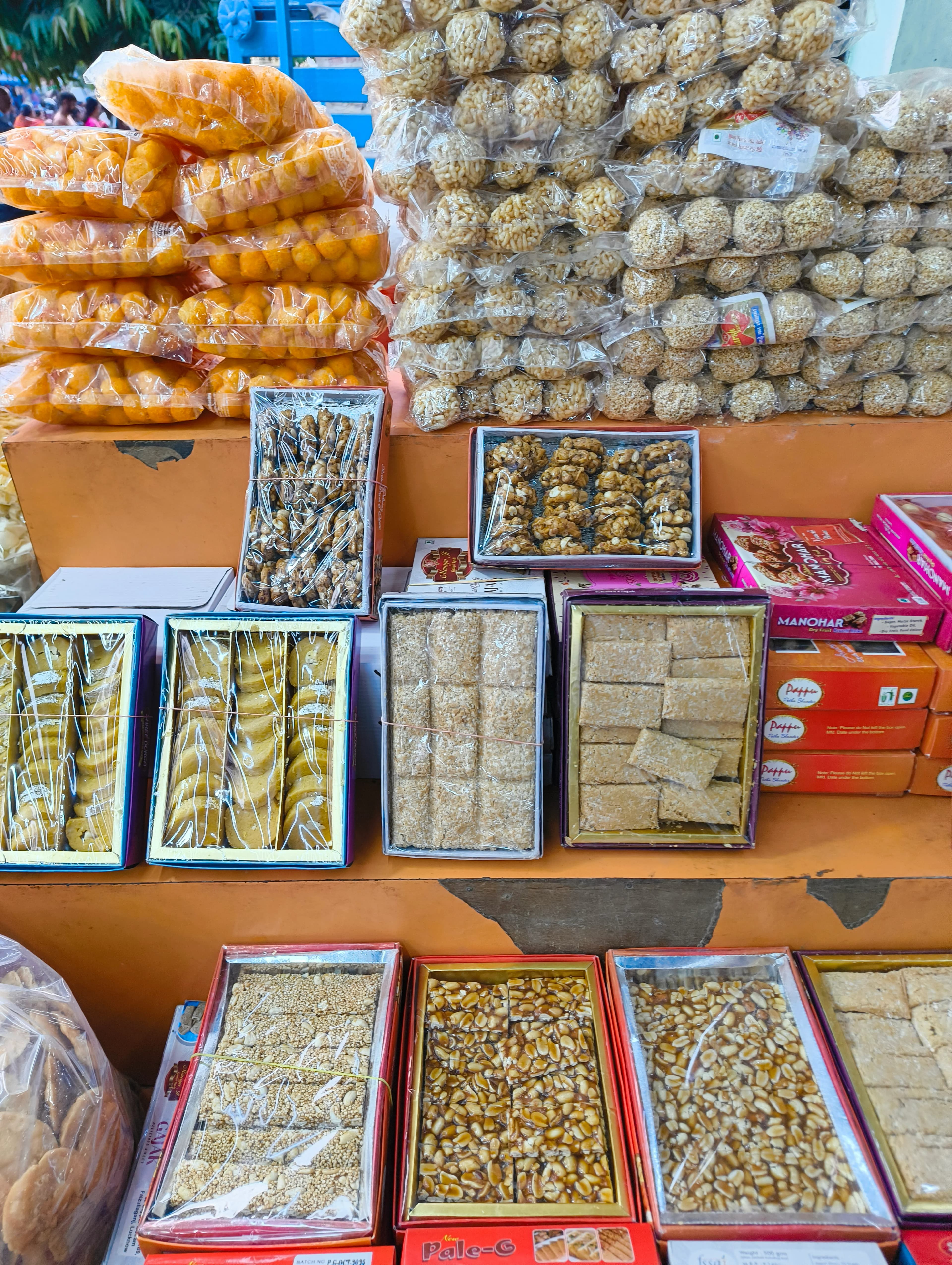 A colourful display of traditional Indian sweets and snacks at a market stall.