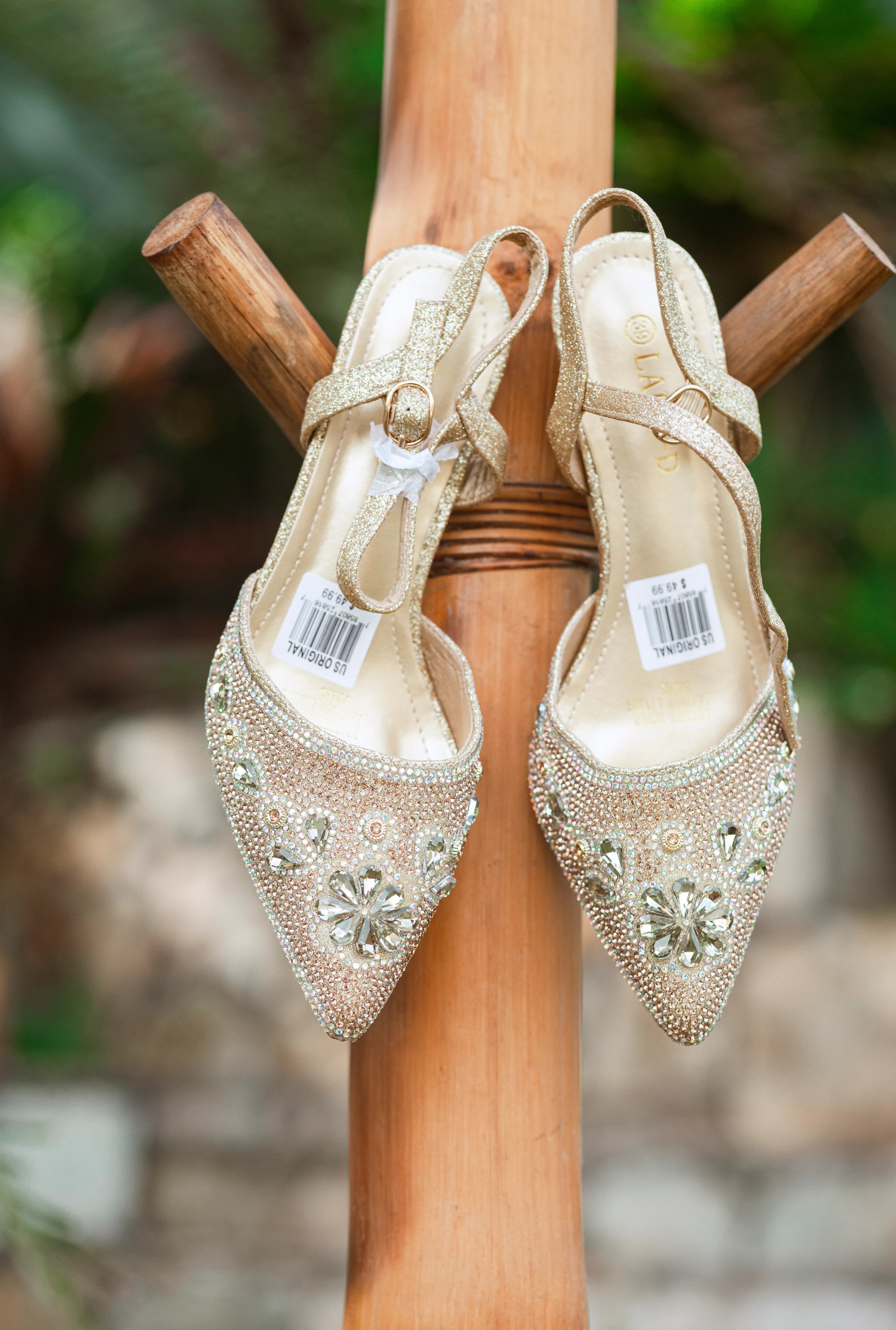 Close-up of gold high heels decorated with intricate beadwork, displayed outdoors.
