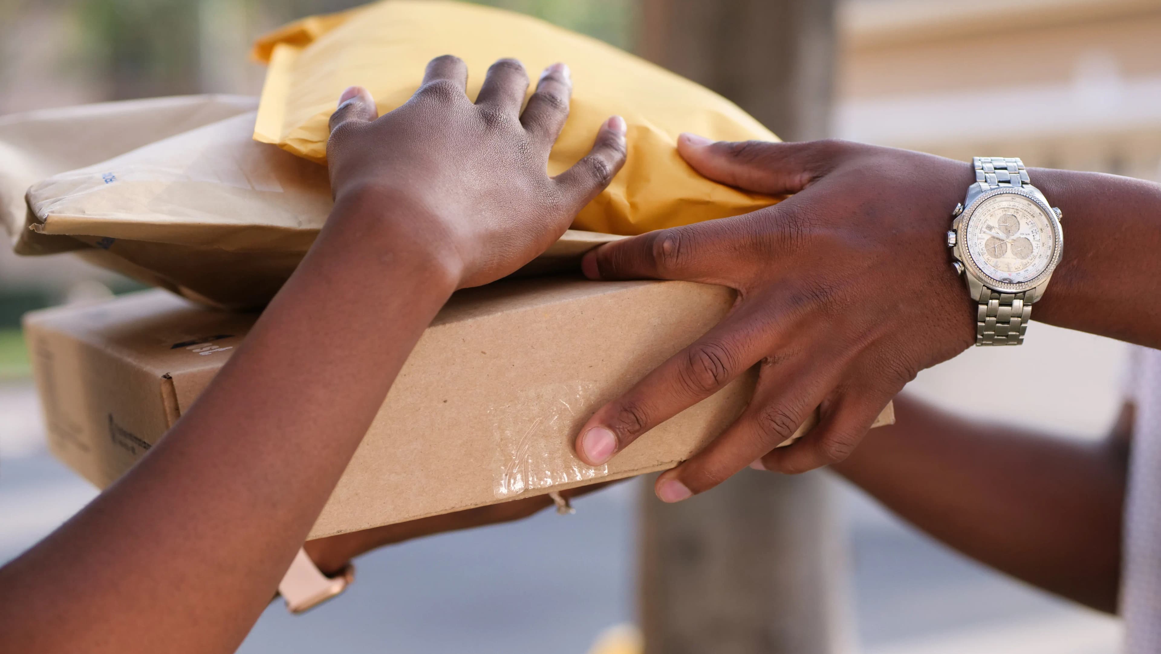 Two people exchanging cardboard boxes and padded envelopes during a parcel handover.